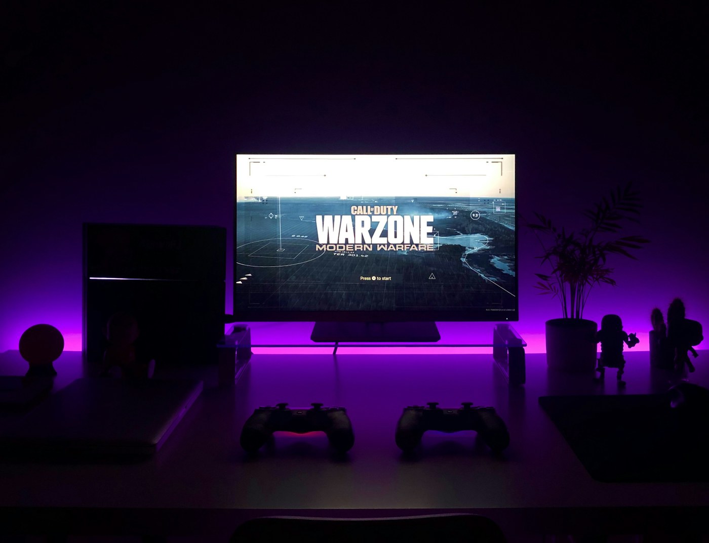 A home gaming monitor and computer setup lit with purple accent lighting