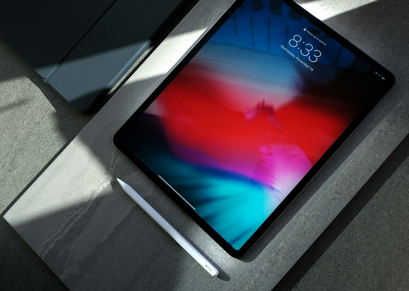 A tablet resting on a dark desk beside other everyday devices