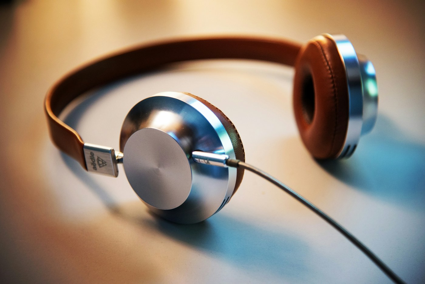 Over-ear headphones resting on a wooden table in a softly lit room
