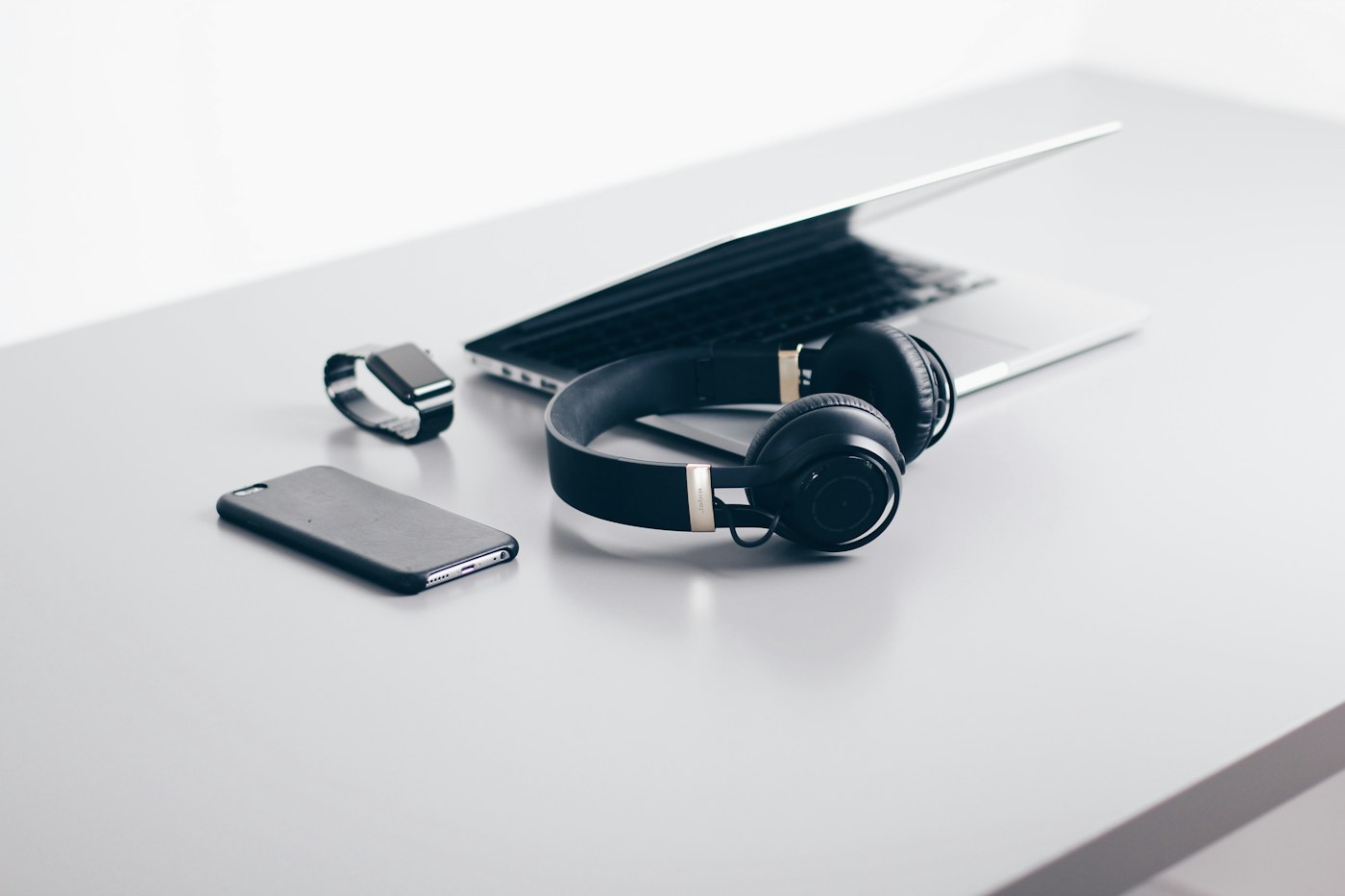 A laptop, smartphone and headphones arranged on a desk